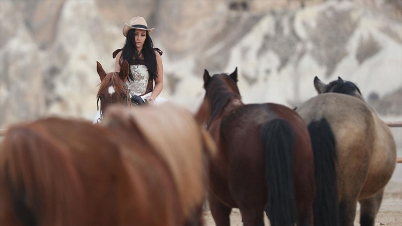 Turistler, Kapadokya’da tarihi kostümlerle at üstünde objektif karşısına geçiyor